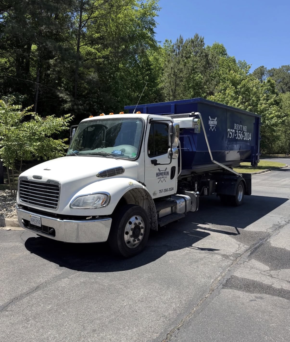 Homerun Hauling roll-off truck delivering a navy dumpster in Hampton Roads